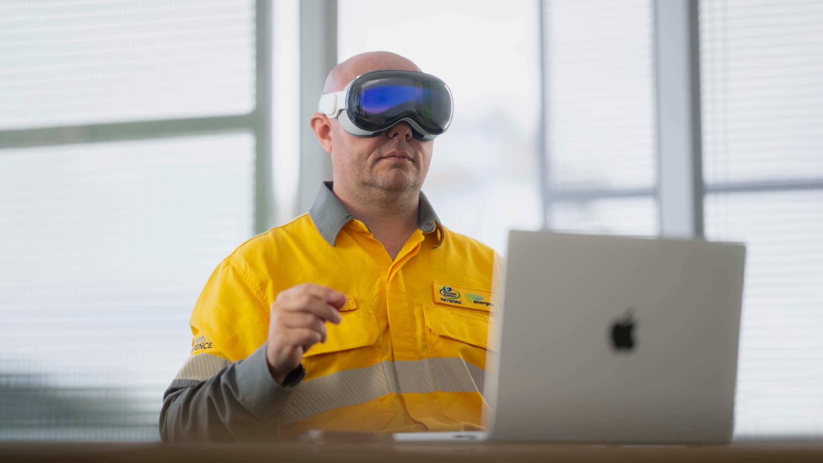Energy Queensland team member exploring a spatial headset alongside a MacBook.
